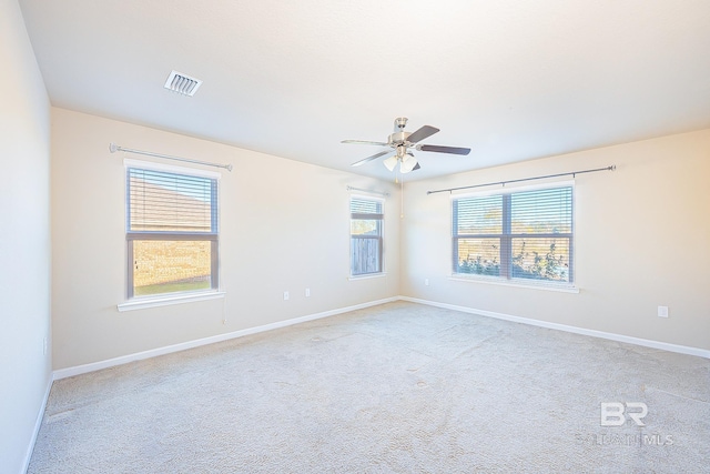 spare room featuring ceiling fan, light carpet, and a wealth of natural light