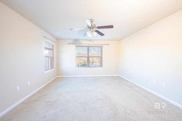 empty room with light colored carpet, ceiling fan, and a healthy amount of sunlight