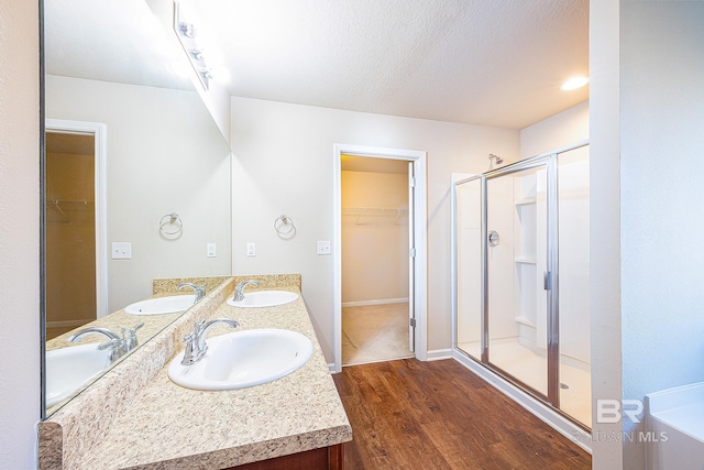 bathroom featuring wood-type flooring, vanity, rail lighting, and a shower with door