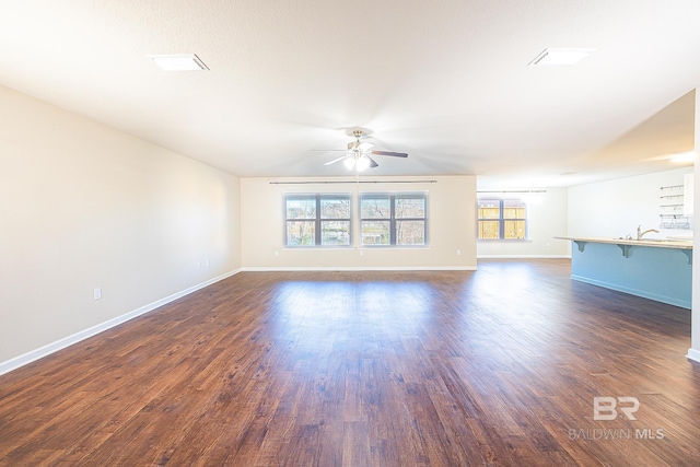 unfurnished living room with dark hardwood / wood-style floors and ceiling fan