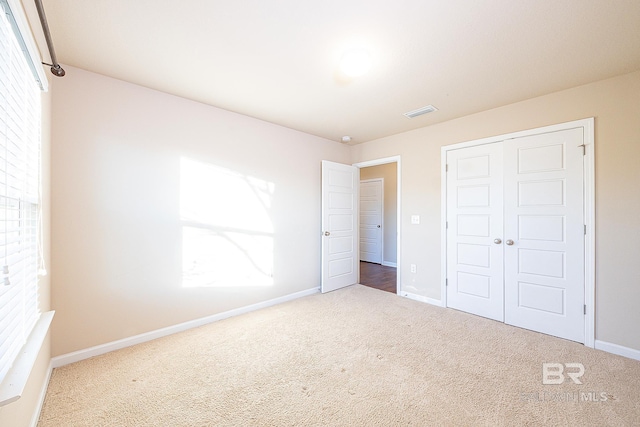 unfurnished bedroom with carpet flooring, multiple windows, and a closet