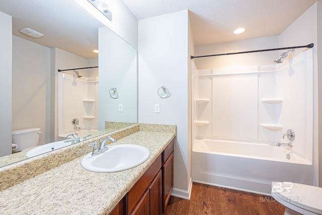 full bathroom featuring washtub / shower combination, wood-type flooring, a textured ceiling, toilet, and vanity