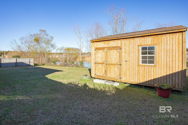 view of outbuilding with a lawn and a water view