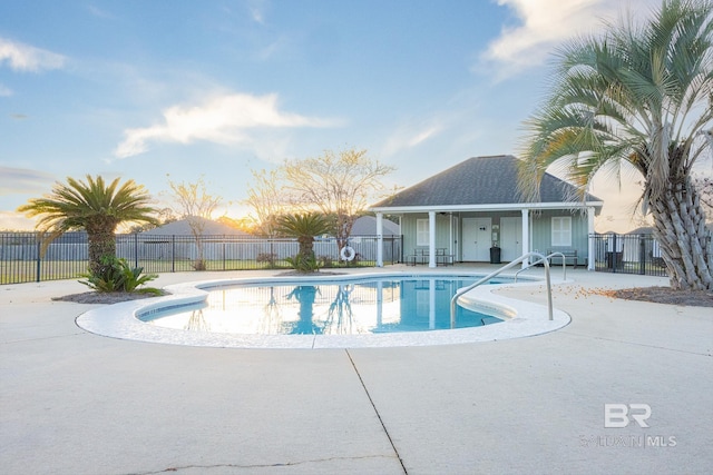 pool at dusk featuring a patio