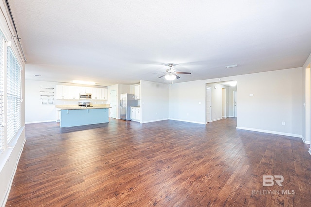 unfurnished living room with a textured ceiling, ceiling fan, and dark hardwood / wood-style floors