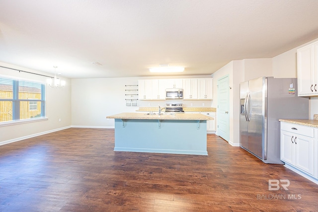 kitchen featuring white cabinets, hanging light fixtures, dark hardwood / wood-style floors, a kitchen bar, and stainless steel appliances