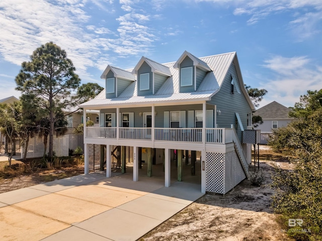 coastal home with covered porch, driveway, a carport, and metal roof