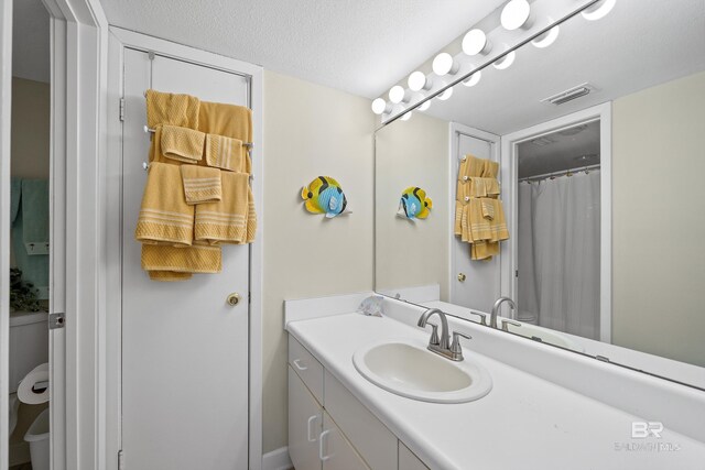 1117 W Beach Blvd Unit 201, Gulf Shores, AL 36542 - full bathroom featuring vanity, toilet, a shower with curtain, and a textured ceiling