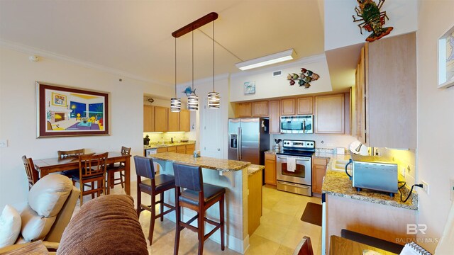 kitchen featuring a breakfast bar, light stone counters, appliances with stainless steel finishes, and decorative light fixtures