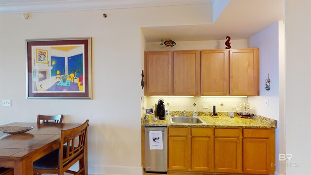 kitchen featuring light stone counters, sink, tasteful backsplash, and stainless steel dishwasher