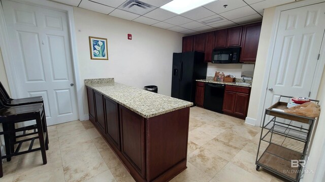 kitchen with light stone counters, sink, kitchen peninsula, a drop ceiling, and black appliances