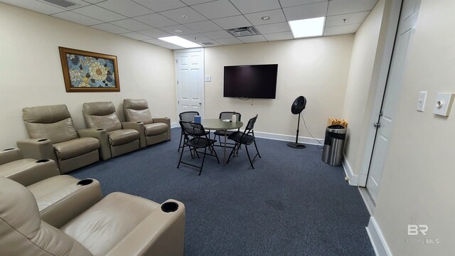 carpeted living room featuring a drop ceiling