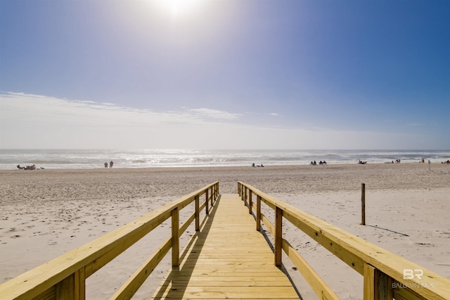 view of dock with a beach view and a water view