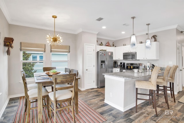 kitchen with a peninsula, appliances with stainless steel finishes, an inviting chandelier, dark wood finished floors, and crown molding