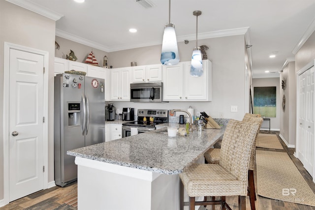 kitchen with a peninsula, visible vents, stainless steel appliances, and ornamental molding