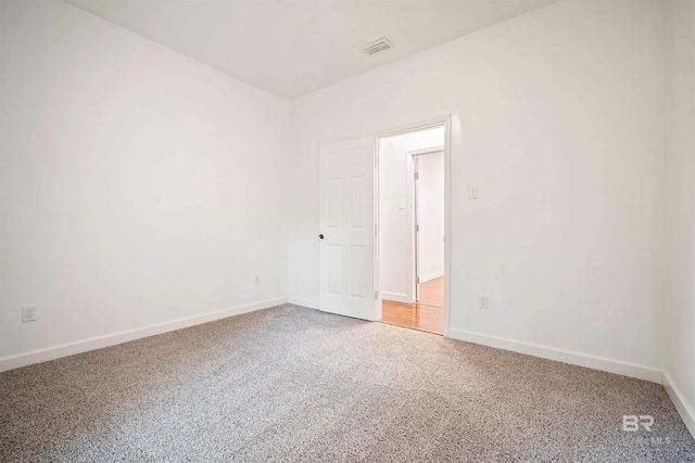 unfurnished room with carpet, visible vents, and baseboards