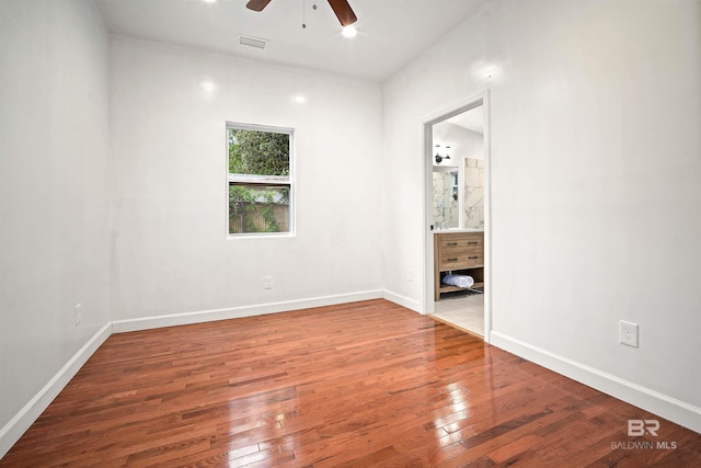 unfurnished bedroom with wood-type flooring, visible vents, baseboards, and ensuite bathroom