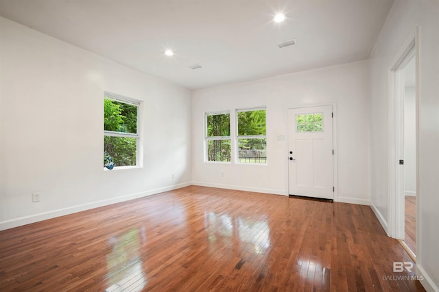 spare room with plenty of natural light, wood-type flooring, visible vents, and baseboards