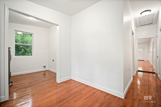 spare room featuring attic access, baseboards, and hardwood / wood-style floors