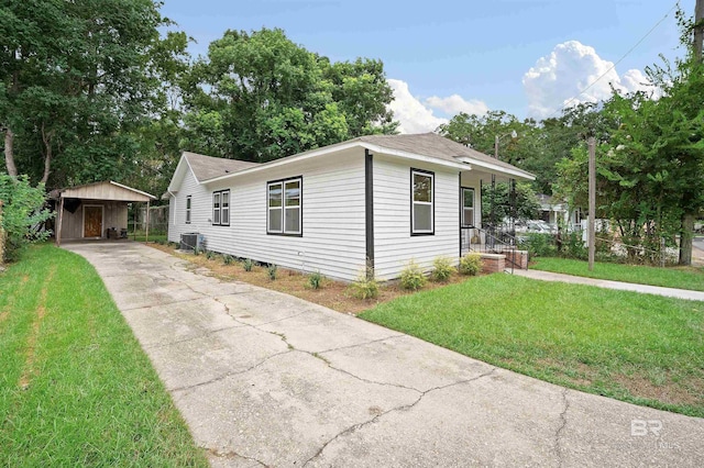 view of front facade with central AC unit, an outbuilding, concrete driveway, and a front yard