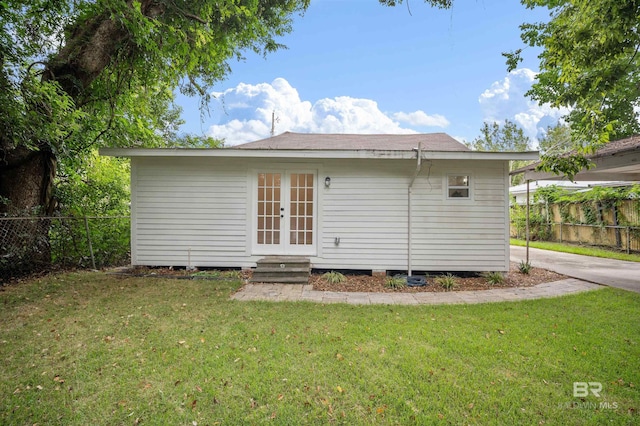 rear view of property with a carport, french doors, a lawn, and fence