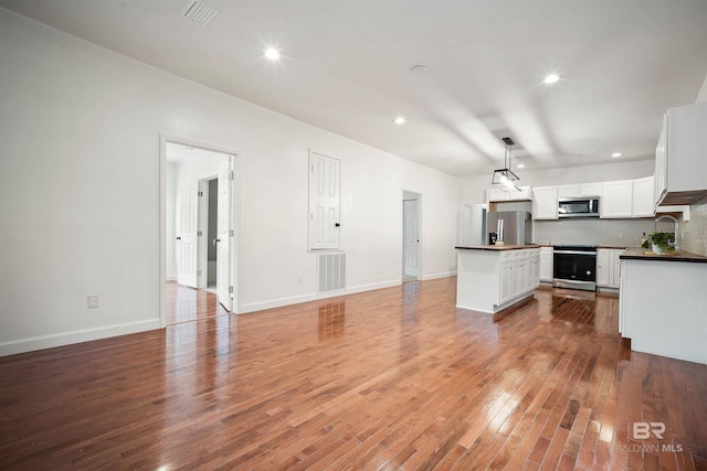 kitchen with dark countertops, tasteful backsplash, visible vents, and stainless steel appliances