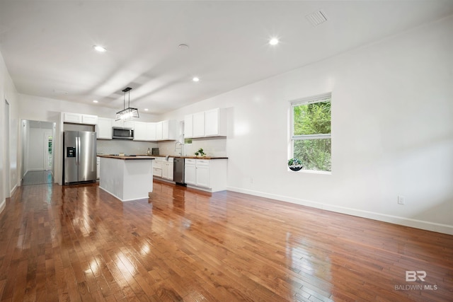 kitchen featuring white cabinets, appliances with stainless steel finishes, hardwood / wood-style floors, and tasteful backsplash