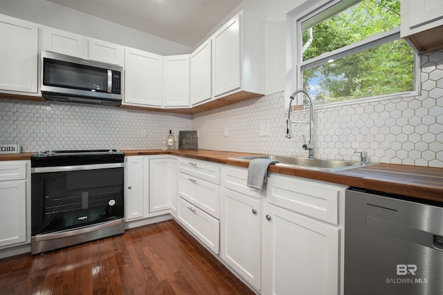 kitchen with appliances with stainless steel finishes, wooden counters, decorative backsplash, and a sink