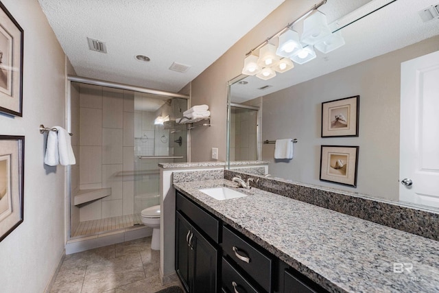 bathroom with tile patterned flooring, vanity, a textured ceiling, toilet, and walk in shower