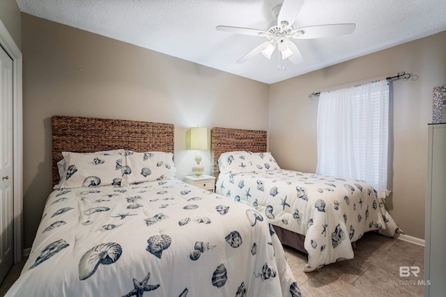 bedroom with a textured ceiling, ceiling fan, and light tile patterned flooring