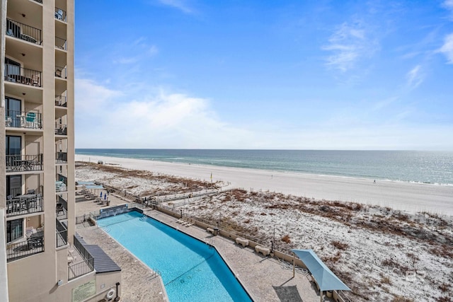 view of swimming pool with a patio area, a beach view, and a water view