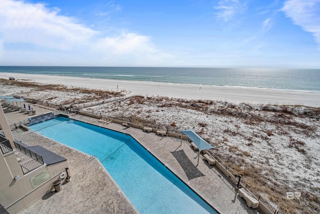 view of swimming pool with a patio, a water view, and a view of the beach