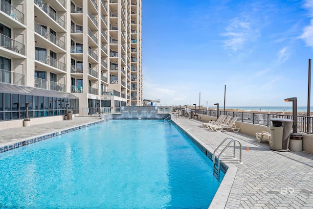 view of swimming pool featuring a water view and a patio area