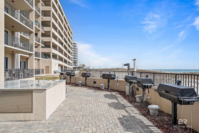 view of patio / terrace with a water view, a grill, and a beach view