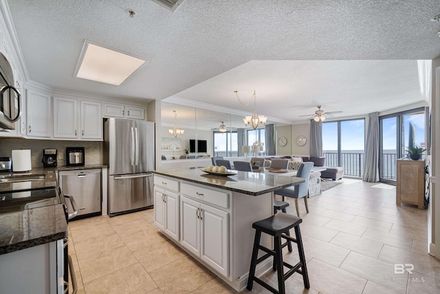 kitchen featuring crown molding, appliances with stainless steel finishes, a center island, white cabinets, and decorative backsplash