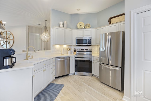 kitchen with light countertops, decorative backsplash, appliances with stainless steel finishes, a sink, and light wood-type flooring