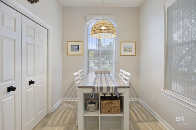 dining space with light wood-style flooring and baseboards