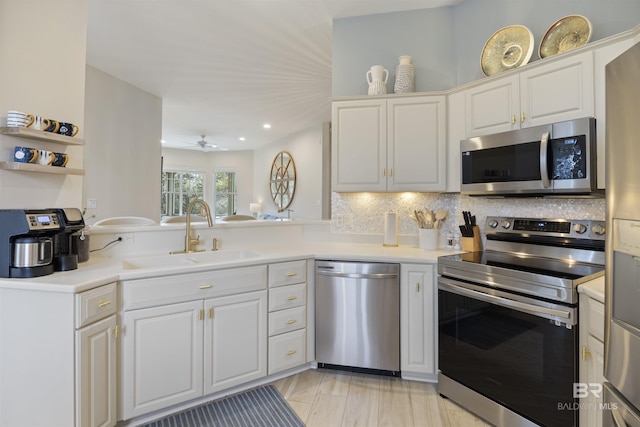 kitchen with appliances with stainless steel finishes, light countertops, a sink, and tasteful backsplash