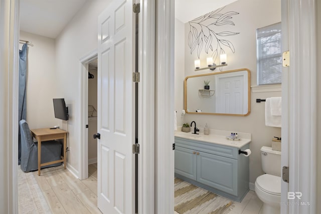 bathroom featuring vanity, wood finished floors, toilet, and baseboards