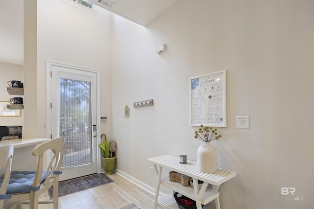 doorway to outside featuring visible vents, baseboards, and wood finished floors