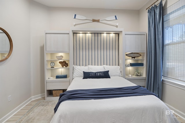 bedroom with multiple windows, light wood-style flooring, and baseboards