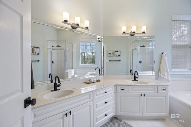 full bathroom with a stall shower, double vanity, a sink, and a bath