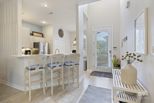 entryway featuring light wood-type flooring, visible vents, and baseboards