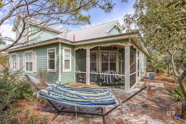 rear view of property with a sunroom, ceiling fan, metal roof, and cooling unit