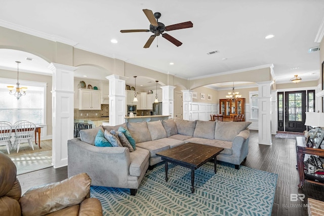 living room featuring dark hardwood / wood-style flooring, ceiling fan with notable chandelier, and ornamental molding