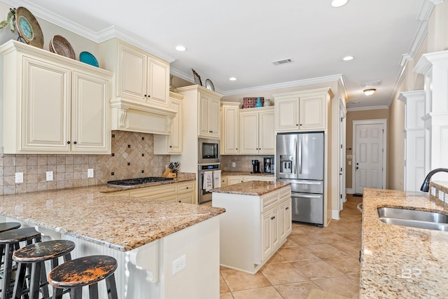 kitchen featuring sink, light stone countertops, stainless steel appliances, and cream cabinets