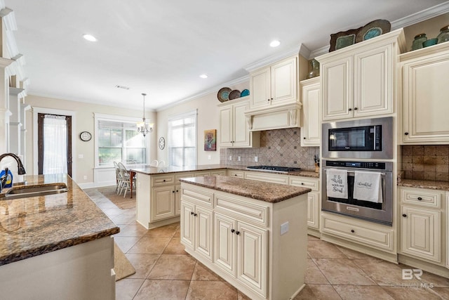 kitchen with pendant lighting, a kitchen island, stainless steel appliances, and cream cabinetry