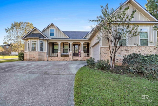 craftsman inspired home with a front lawn, covered porch, and a garage