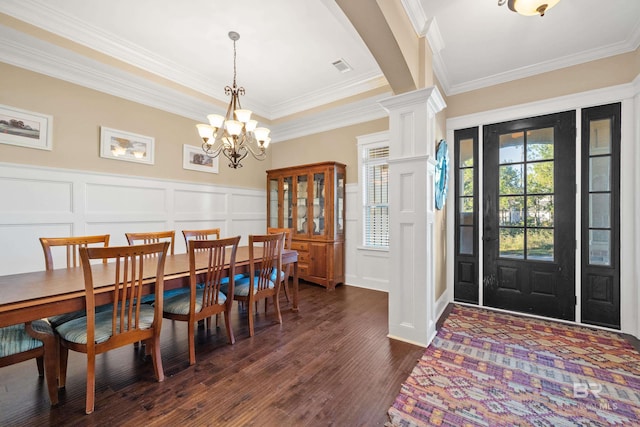 dining area with ornate columns, crown molding, dark wood-type flooring, and a notable chandelier