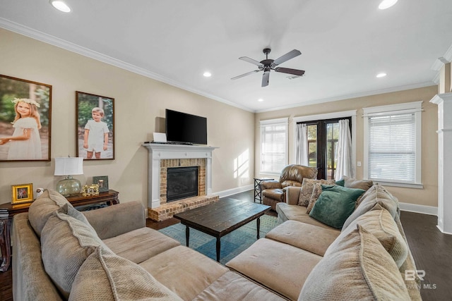 living room featuring a fireplace, ceiling fan, crown molding, and dark wood-type flooring